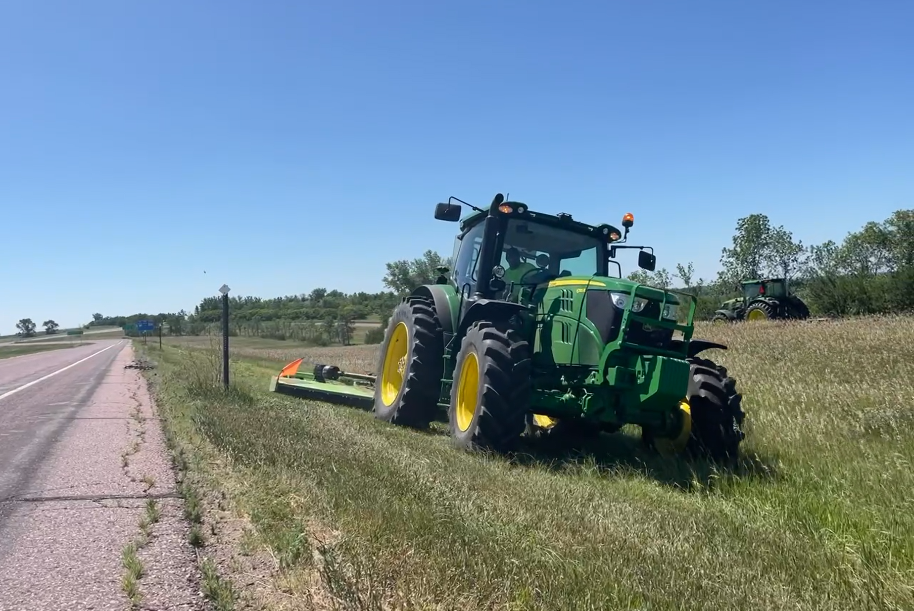 green tractor mower, mowing the state highway ditch in South Dakota